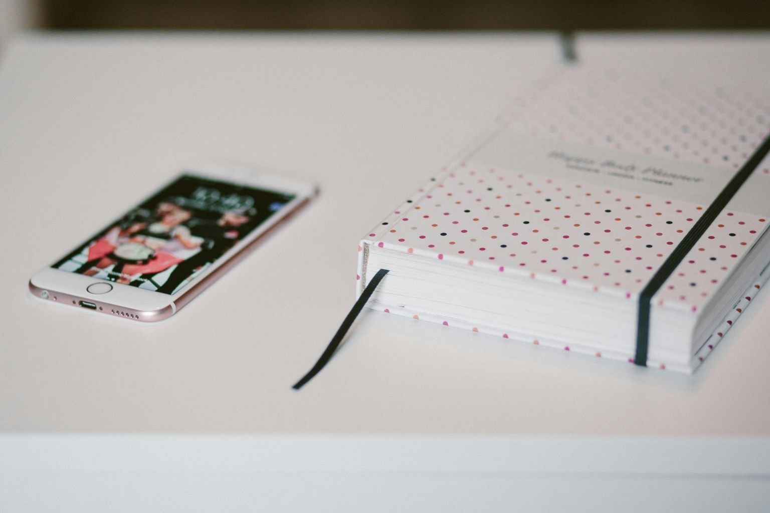 Smartphone and a polka dot planner on a clean white surface, symbolizing organization and technology. 7 Best Productivity Books You Should Read Today